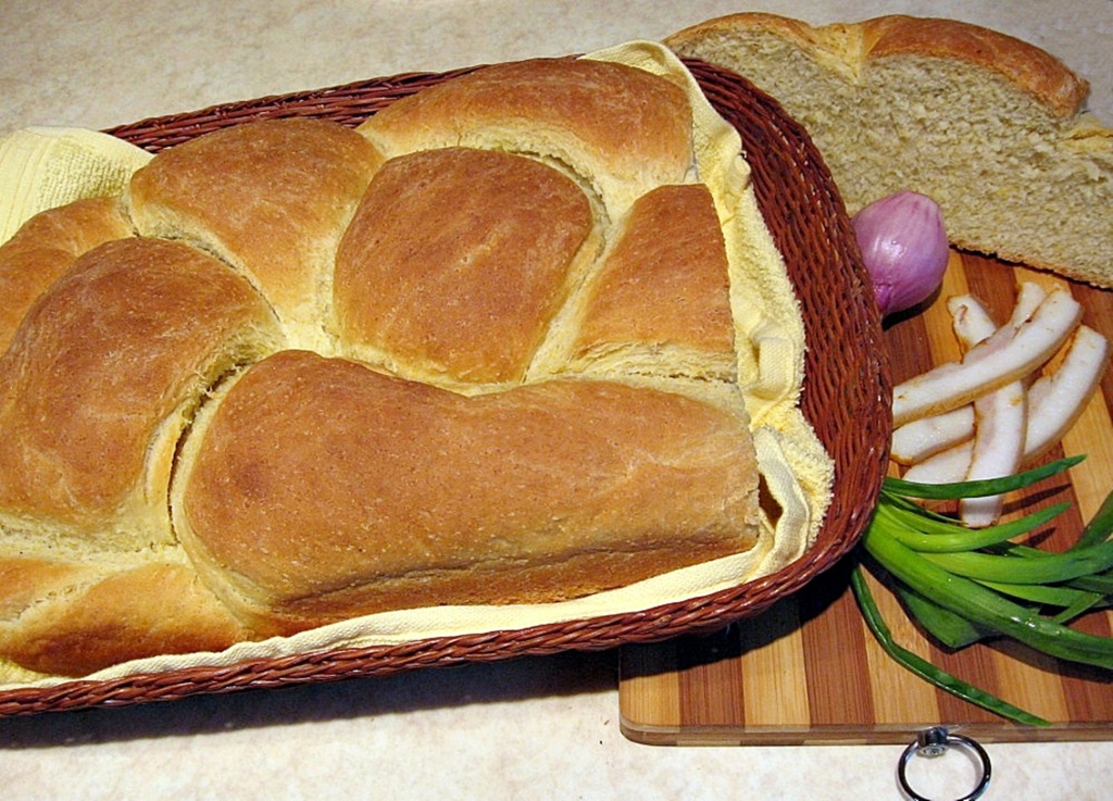Paine cu amestec de faina si malai intr-un cos si o felie de paine pe tocator, alaturi de ceapa rosie si slanina Paine cu amestec de faina si malai intr-un cos si o felie de paine pe tocator, alaturi de ceapa rosie si slanina