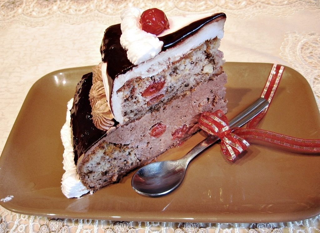 Porție de tort aniversar etajat, cu nucă, vișine și ciocolată Porție de tort aniversar etajat, cu nucă, vișine și ciocolată
