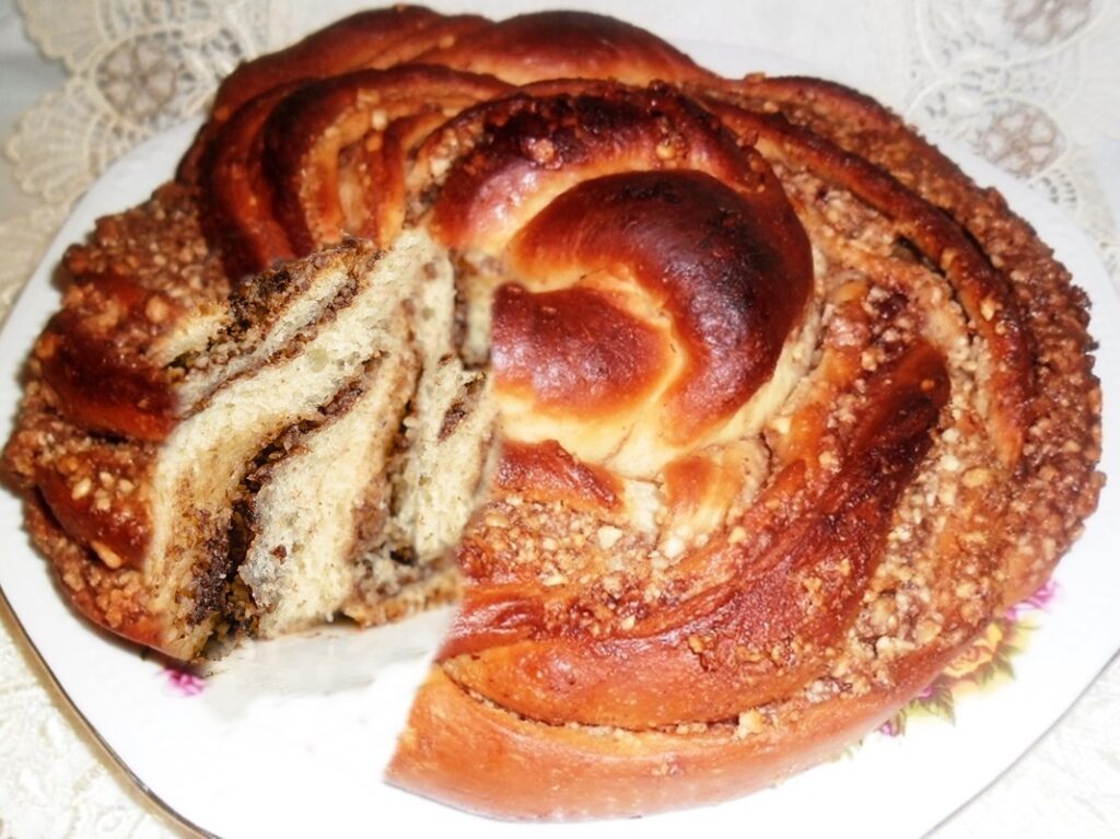 Cozonac trandafir cu nuca si gem de caise sectionat pe platou