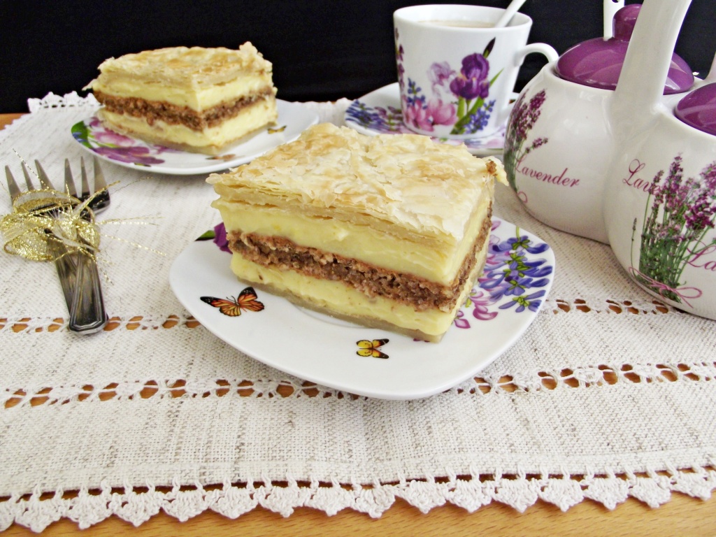 Doua portii de cremes cu foietaj si blat cu nuca, doua furculite si un set de cafea Doua portii de cremes cu foietaj si blat cu nuca, doua furculite si un set de cafea