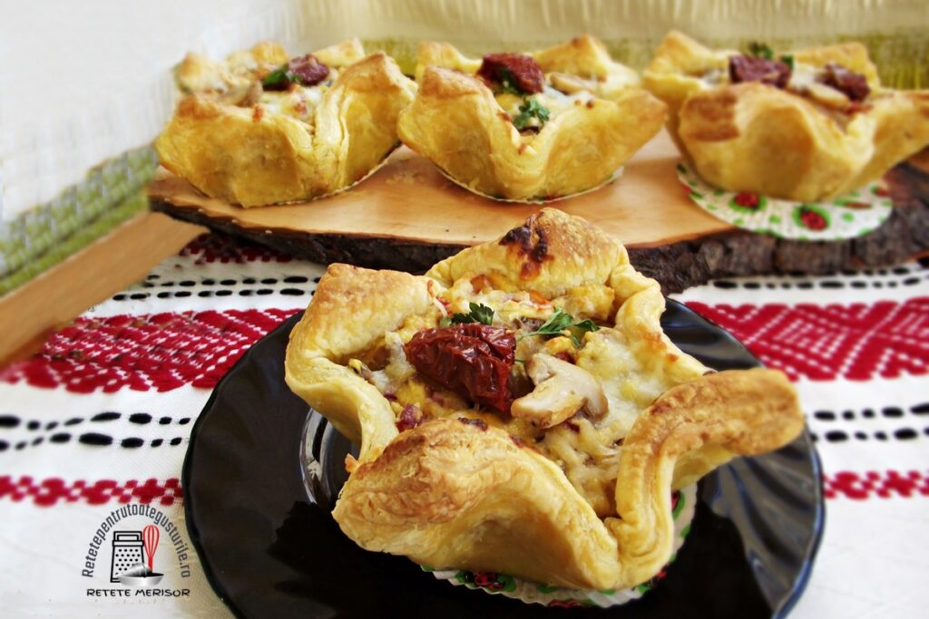 Cosulete aperitiv din foietaj cu bacon si ciuperci pe un platou de lemn si pe o farfurie neagra