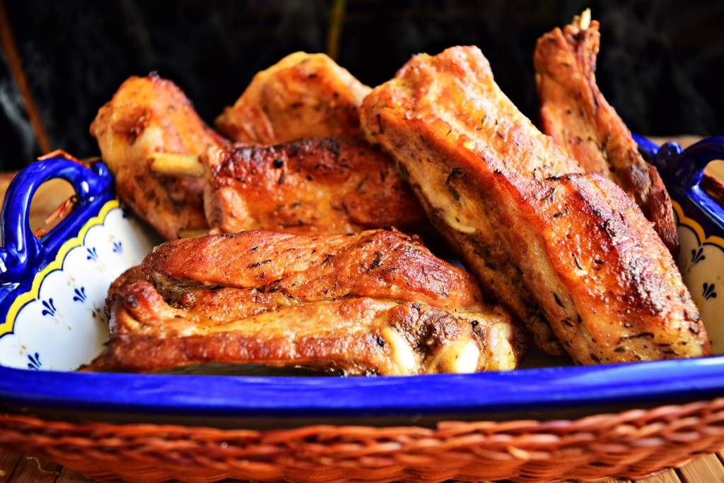 Coaste de porc dulci-picante într-o tavă de porțelan albastră, așezată într-un coș de nuiele, împletit