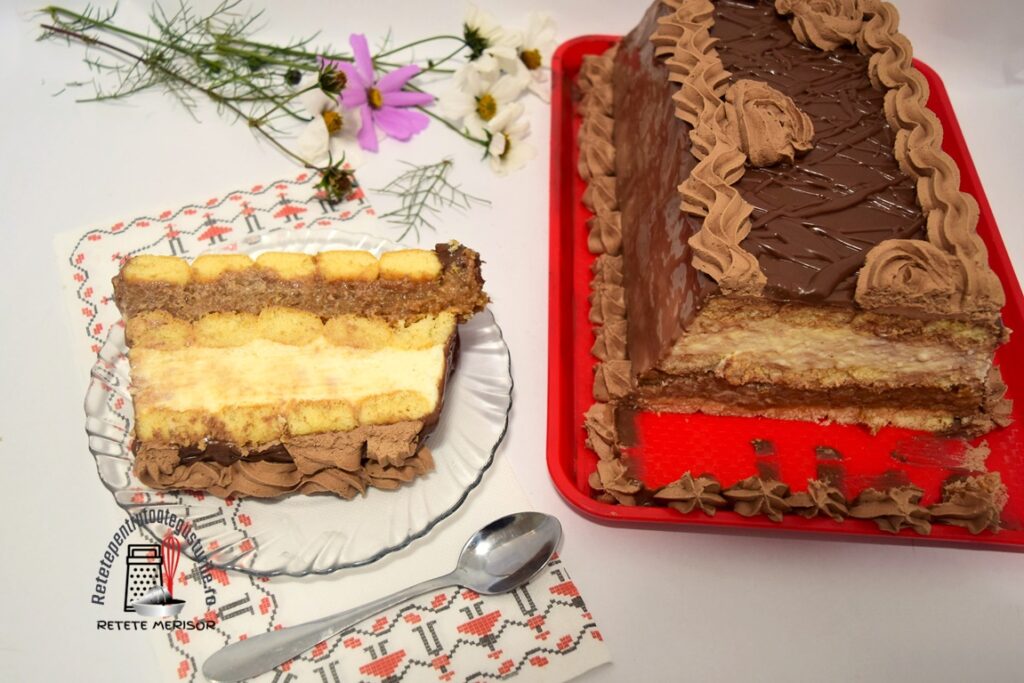 Porție de Tort cu mere și budincă de griș pe o farfurie de sticlă, alături de platoul cu tort