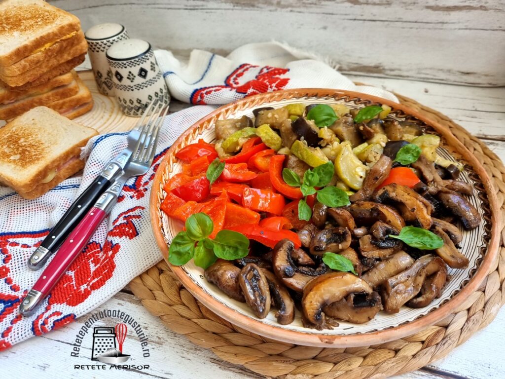Farfurie rustică cu Legume la tigaie cu usturoi și busuioc. alături de un ștergar rustic cu tacâmuri pe el și felii de pâine prăjite