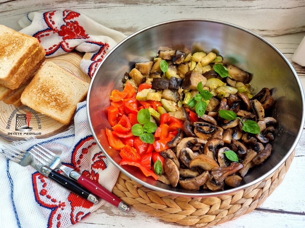 Bol de inox cu legume la tigaie cu usturoi și busuioc. alături de un ștergar rustic cu tacâmuri pe el și felii de pâine prăjite
