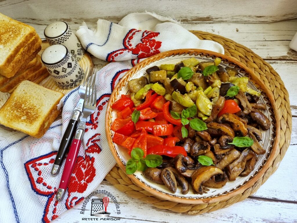 Farfurie rustică cu Legume la tigaie cu usturoi și busuioc. alături de un ștergar rustic cu tacâmuri pe el și felii de pâine prăjite