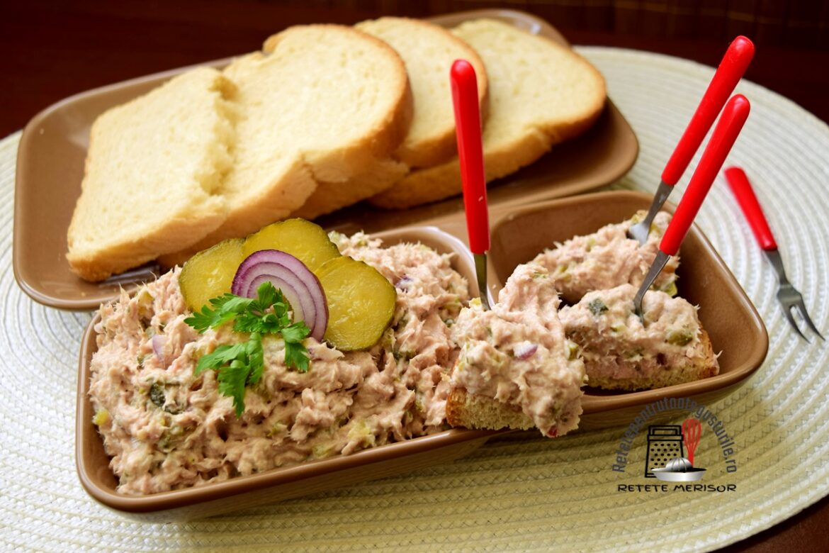 Pastă de ton cu hering afumat, castraveciori și ceapă roșie pe un platou maro cu furculițe roșii și felii de pâine